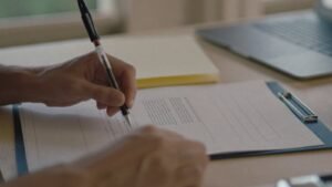 Maos preenchendo um formulario de abertura de atividade com carimbo ao lado